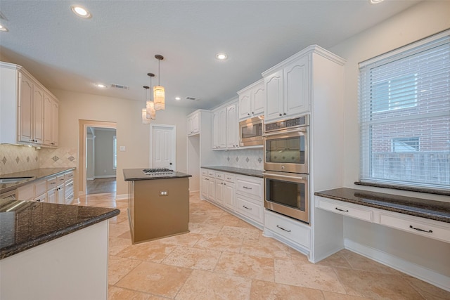 9 Foxworth Ct, Sugar Land, TX 77479 - kitchen with appliances with stainless steel finishes, backsplash, dark stone countertops, pendant lighting, and white cabinetry