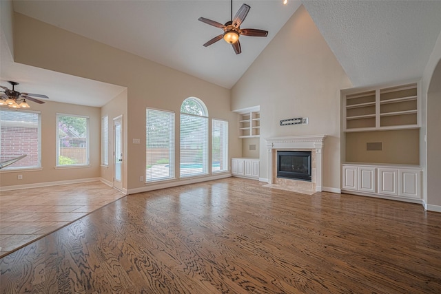 9 Foxworth Ct, Sugar Land, TX 77479 - unfurnished living room with built in shelves, a ceiling fan, wood finished floors, high vaulted ceiling, and a fireplace with flush hearth