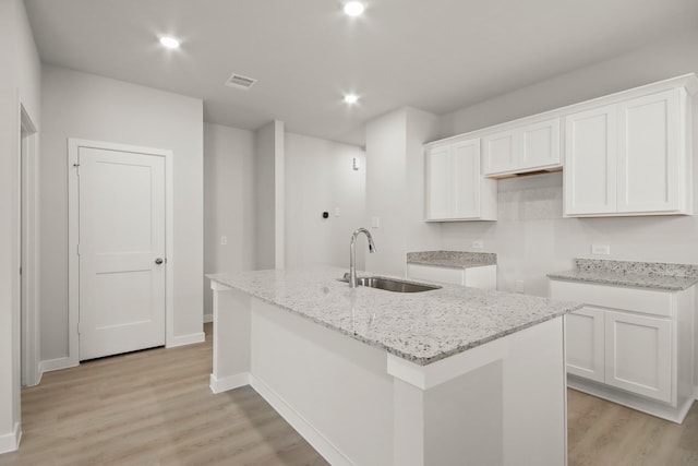 7826 Ruthie Ravine Ct, Spring, TX 77379 - kitchen featuring light stone countertops, light wood finished floors, a center island with sink, white cabinets, and recessed lighting