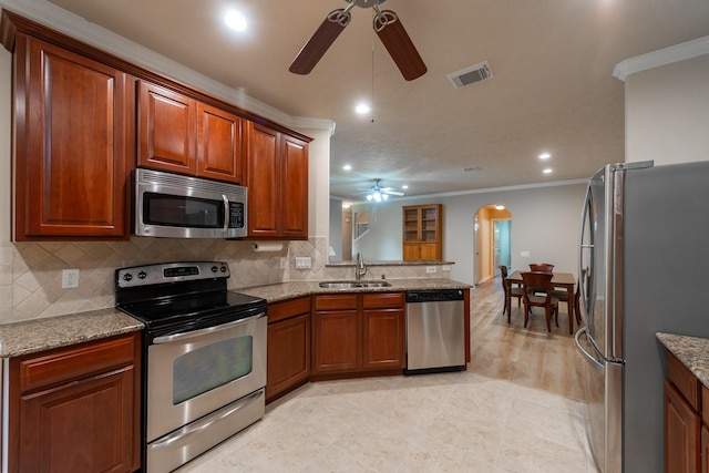 5242 Garnetfield Ln, Katy, TX 77494 - kitchen featuring stainless steel appliances, a ceiling fan, crown molding, arched walkways, and tasteful backsplash