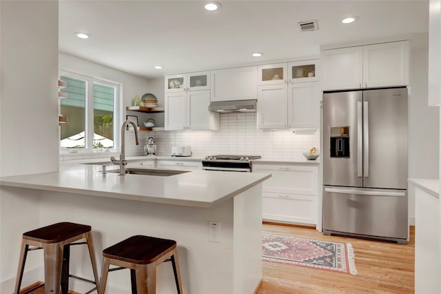 1039 Lamonte Ln, Houston, TX 77018 - kitchen with stainless steel appliances, a kitchen bar, light wood finished floors, white cabinets, and recessed lighting