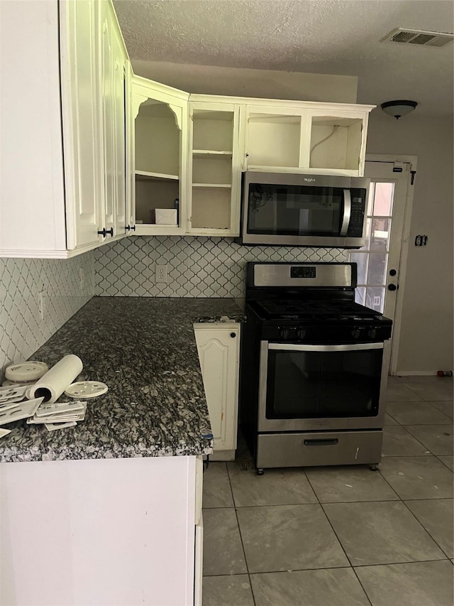 1207 Dwinnell St, Baytown, TX 77520 - kitchen featuring appliances with stainless steel finishes, light tile patterned floors, decorative backsplash, open shelves, and a textured ceiling