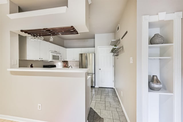 1330 Old Spanish Trl Unit 1210, Houston, TX 77054 - kitchen with white microwave, freestanding refrigerator, white cabinets, a peninsula, and light countertops