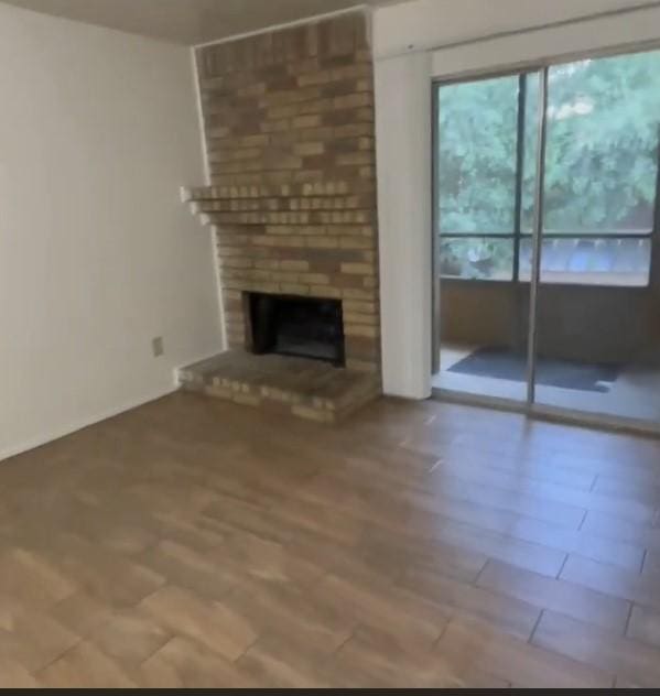 10555 Turtlewood Ct Unit 2303, Houston, TX 77072 - unfurnished living room featuring a brick fireplace and wood finished floors