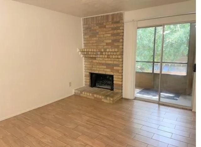 10555 Turtlewood Ct Unit 2303, Houston, TX 77072 - unfurnished living room featuring wood finished floors and a brick fireplace
