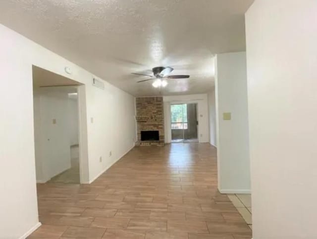 10555 Turtlewood Ct Unit 2303, Houston, TX 77072 - unfurnished living room featuring ceiling fan, a fireplace, and a textured ceiling