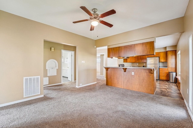 5302 Pine Ave, Pasadena, TX 77503 - kitchen featuring freestanding refrigerator, brown cabinets, carpet, and a kitchen breakfast bar