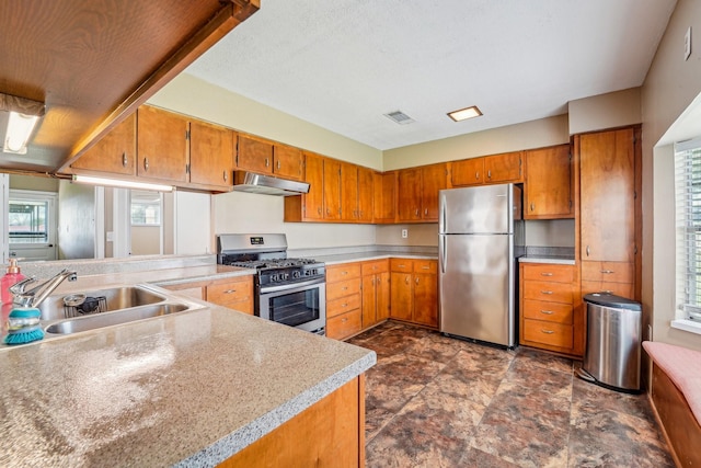5302 Pine Ave, Pasadena, TX 77503 - kitchen featuring appliances with stainless steel finishes, under cabinet range hood, brown cabinets, and light countertops