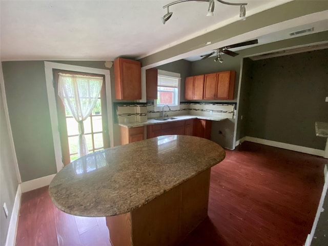 212 Harding Ave, Cleveland, TX 77327 - kitchen featuring brown cabinets, dark wood-style flooring, a kitchen island, and decorative backsplash