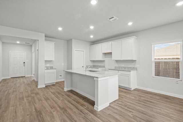316 Amy St, Angleton, TX 77515 - kitchen with light wood-style floors, a center island with sink, white cabinetry, recessed lighting, and light stone countertops