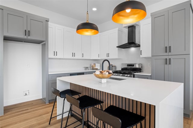 6907 Conley St, Houston, TX 77021 - kitchen featuring wall chimney exhaust hood, stainless steel range, light countertops, light wood-style flooring, and recessed lighting