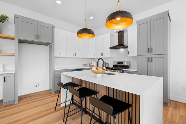 6907 Conley St, Houston, TX 77021 - kitchen featuring wall chimney range hood, stainless steel stove, light wood finished floors, light countertops, and recessed lighting