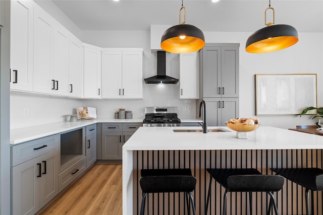 6907 Conley St, Houston, TX 77021 - kitchen featuring stainless steel range, wall chimney range hood, gray cabinets, and a breakfast bar