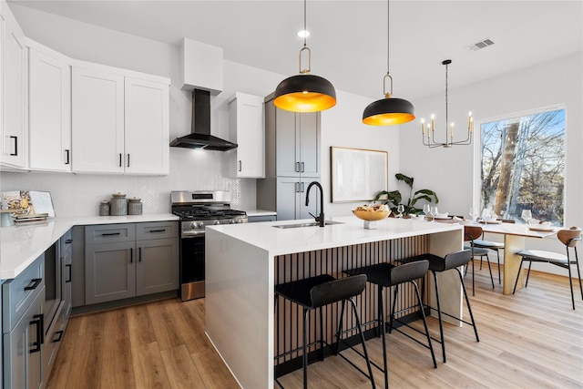 6907 Conley St, Houston, TX 77021 - kitchen with wall chimney exhaust hood, stainless steel gas range oven, light wood-type flooring, decorative backsplash, and light countertops