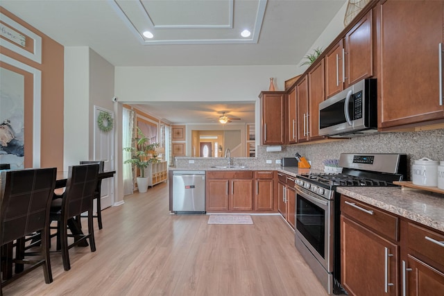 8113 E Pine Creek Bnd, Cypress, TX 77433 - kitchen with appliances with stainless steel finishes, light wood-style floors, tasteful backsplash, brown cabinetry, and recessed lighting