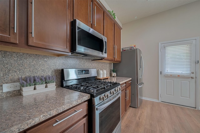 8113 E Pine Creek Bnd, Cypress, TX 77433 - kitchen with appliances with stainless steel finishes, light wood-style floors, decorative backsplash, and brown cabinets