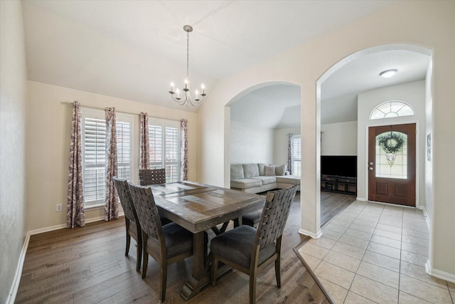 9111 Kinnel Ln, Tomball, TX 77375 - dining space with arched walkways, vaulted ceiling, a chandelier, and light wood-style floors