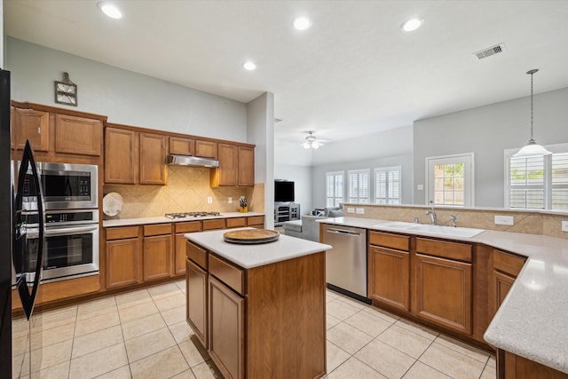9111 Kinnel Ln, Tomball, TX 77375 - kitchen featuring stainless steel appliances, brown cabinets, tasteful backsplash, a kitchen island, and light tile patterned floors