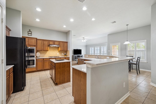 9111 Kinnel Ln, Tomball, TX 77375 - kitchen featuring stainless steel appliances, a spacious island, light tile patterned flooring, brown cabinetry, and recessed lighting