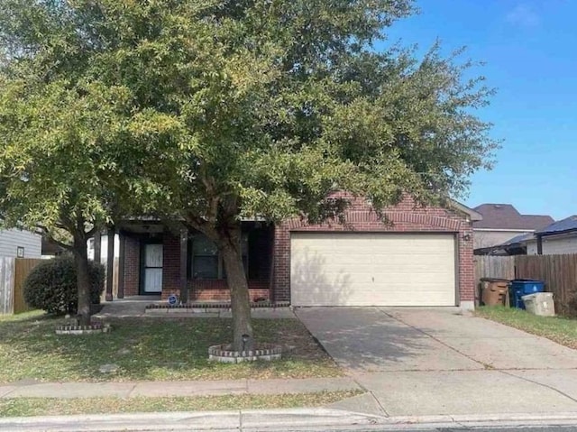 5608 Nijmegen Dr, Del Valle, TX 78617 - view of property hidden behind natural elements with an attached garage, brick siding, and driveway