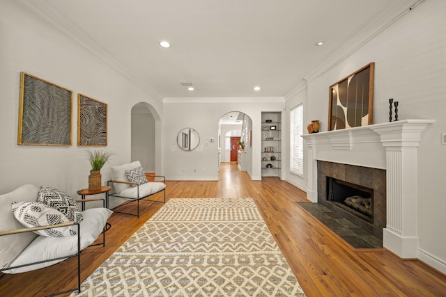 1931 Woodbury St, Houston, TX 77030 - living room with arched walkways, wood finished floors, crown molding, recessed lighting, and a tile fireplace