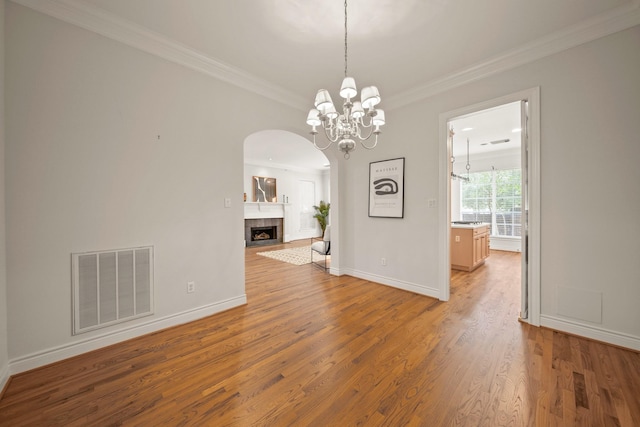 1931 Woodbury St, Houston, TX 77030 - empty room with arched walkways, wood finished floors, crown molding, a chandelier, and a tile fireplace