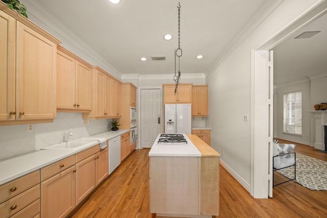1931 Woodbury St, Houston, TX 77030 - kitchen featuring white appliances, ornamental molding, light brown cabinets, a kitchen island, and light wood-style flooring