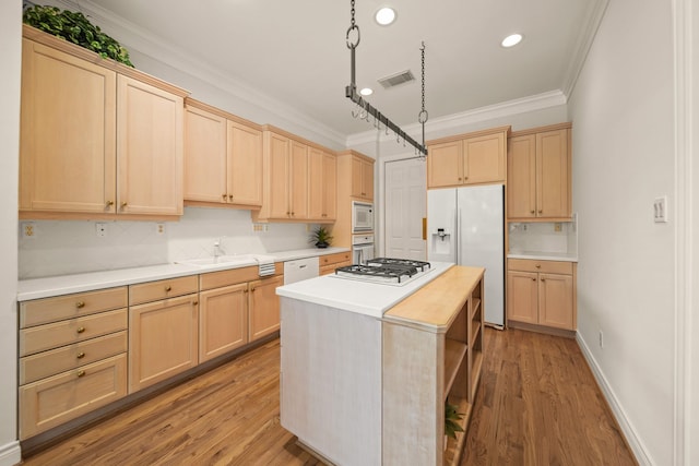 1931 Woodbury St, Houston, TX 77030 - kitchen featuring white appliances, light brown cabinetry, ornamental molding, light countertops, and light wood-style floors