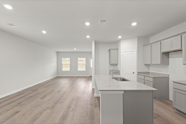 436 Shoreview Dr, Conroe, TX 77303 - kitchen featuring gray cabinetry, a kitchen island with sink, recessed lighting, light stone counters, and light wood-style floors