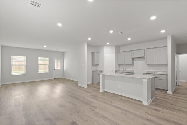 436 Shoreview Dr, Conroe, TX 77303 - kitchen with gray cabinetry, a center island with sink, recessed lighting, light wood-style flooring, and open floor plan