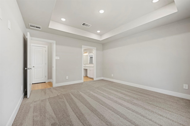 2845 14th St, Hempstead, TX 77445 - unfurnished bedroom featuring a raised ceiling, light colored carpet, recessed lighting, and connected bathroom