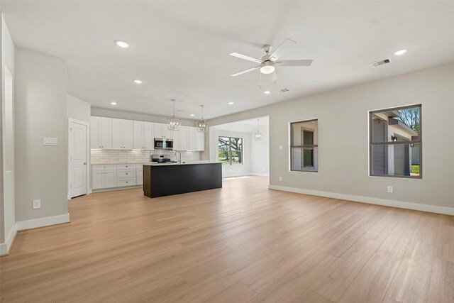 2845 14th St, Hempstead, TX 77445 - kitchen with stainless steel microwave, open floor plan, recessed lighting, white cabinetry, and light wood-style floors
