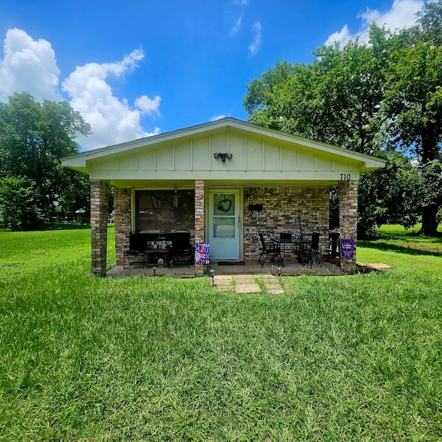 710 College St, El Campo, TX 77437 - view of front of property with a front lawn, board and batten siding, and a patio