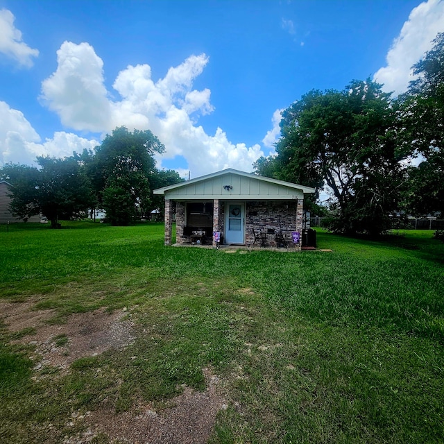 710 College St, El Campo, TX 77437 - rear view of house with a yard and board and batten siding