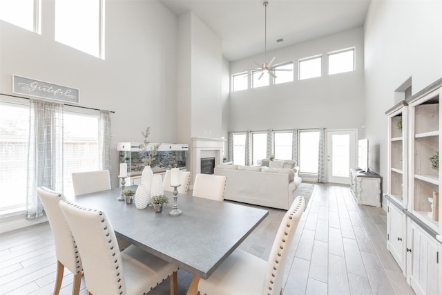 13746 Brahman Valley Ct, Cypress, TX 77429 - dining space featuring a towering ceiling, a ceiling fan, light wood-style flooring, and a glass covered fireplace