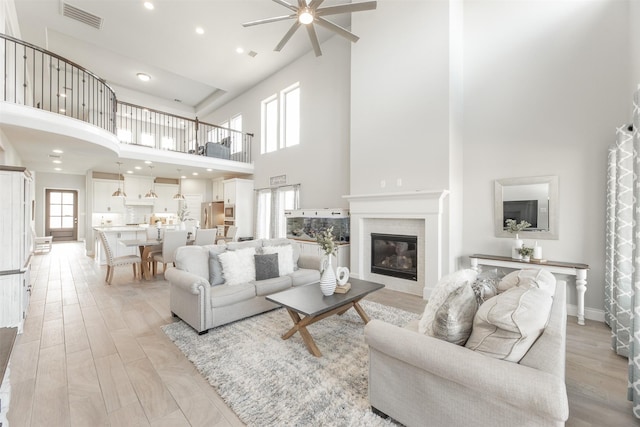 13746 Brahman Valley Ct, Cypress, TX 77429 - living room with a high ceiling, ceiling fan, a tile fireplace, recessed lighting, and light wood-type flooring