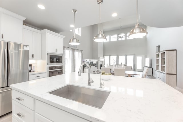13746 Brahman Valley Ct, Cypress, TX 77429 - kitchen with appliances with stainless steel finishes, a towering ceiling, pendant lighting, white cabinetry, and light stone countertops
