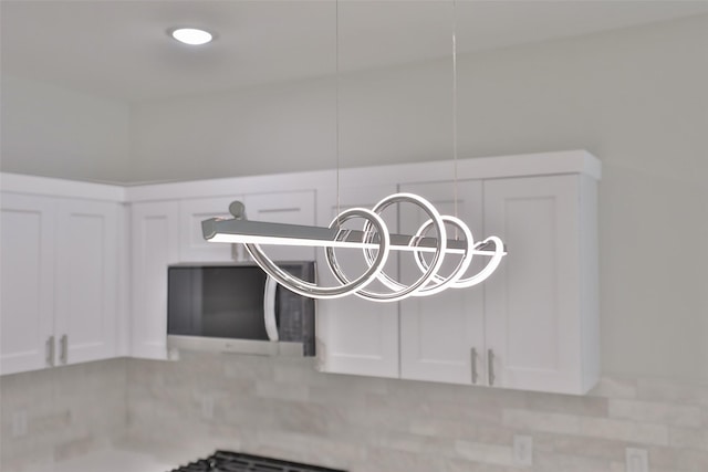 6909 S Hall St, Houston, TX 77028 - kitchen view of stainless steel microwave, white cabinetry, and a chandelier