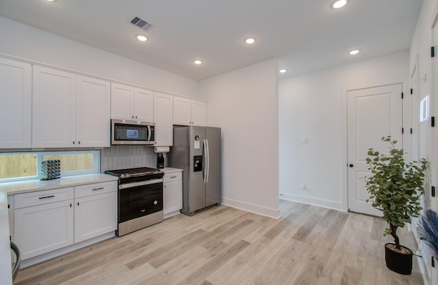 1616 Benson St, Houston, TX 77020 - kitchen with stainless steel appliances, light wood-style flooring, white cabinetry, decorative backsplash, and light countertops
