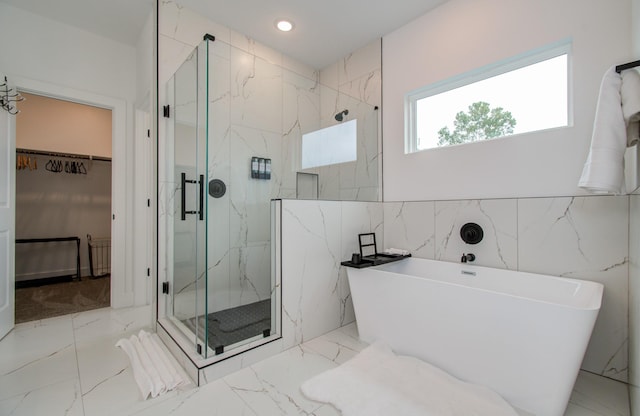 1616 Benson St, Houston, TX 77020 - full bathroom featuring a marble finish shower, a soaking tub, a walk in closet, marble tiled flooring, and tile walls