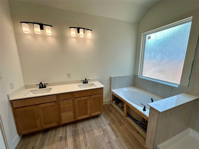 16446 Elk Meadow Dr, Conroe, TX 77302 - bathroom with a bath, wood finished floors, lofted ceiling, and double vanity