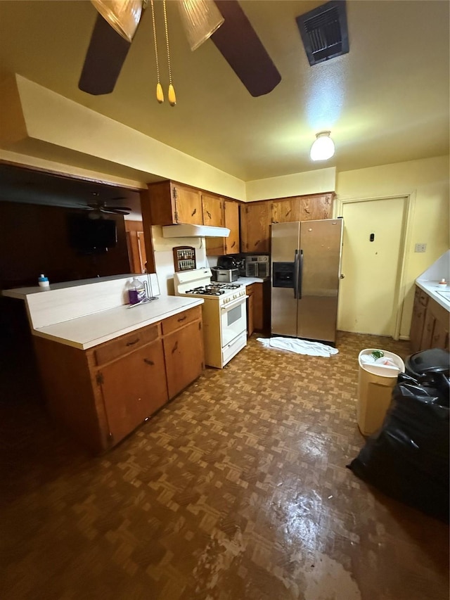4830 Teton St, Houston, TX 77033 - kitchen featuring stainless steel fridge with ice dispenser, white gas range, under cabinet range hood, ceiling fan, and brown cabinets