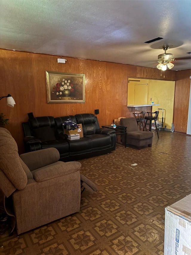 4830 Teton St, Houston, TX 77033 - living room featuring wood walls, ceiling fan, and a textured ceiling