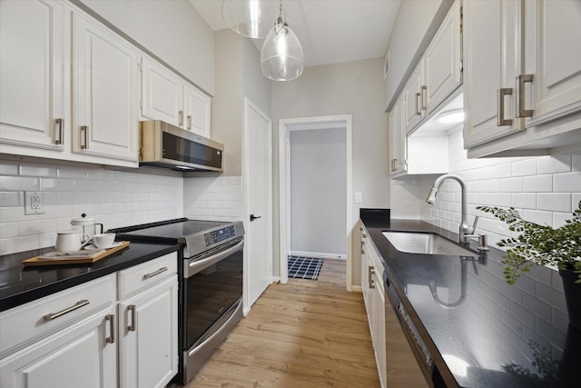 2475 Underwood St Unit 369, Houston, TX 77030 - kitchen featuring stainless steel appliances, dark countertops, white cabinetry, light wood finished floors, and decorative backsplash