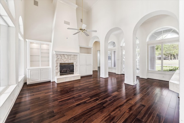 966 Bentwater Dr, Montgomery, TX 77356 - unfurnished living room with a high ceiling, dark wood-style flooring, built in shelves, a ceiling fan, and a stone fireplace