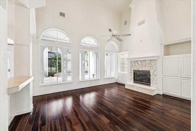 966 Bentwater Dr, Montgomery, TX 77356 - unfurnished living room featuring dark wood-type flooring, a ceiling fan, a towering ceiling, a stone fireplace, and crown molding