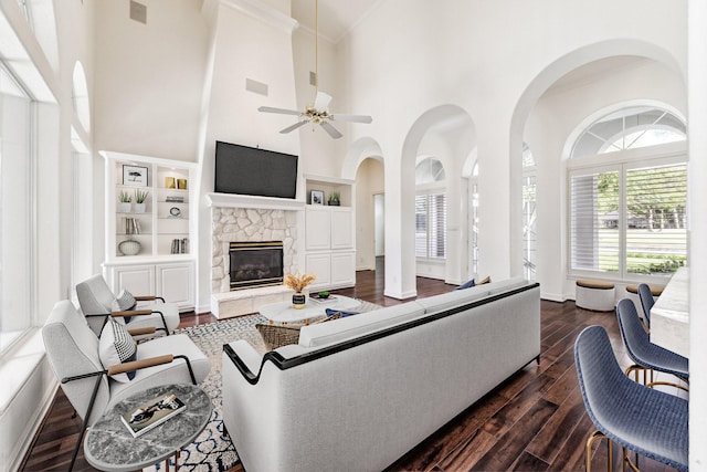 966 Bentwater Dr, Montgomery, TX 77356 - living room with dark wood finished floors, a ceiling fan, a towering ceiling, a stone fireplace, and built in shelves