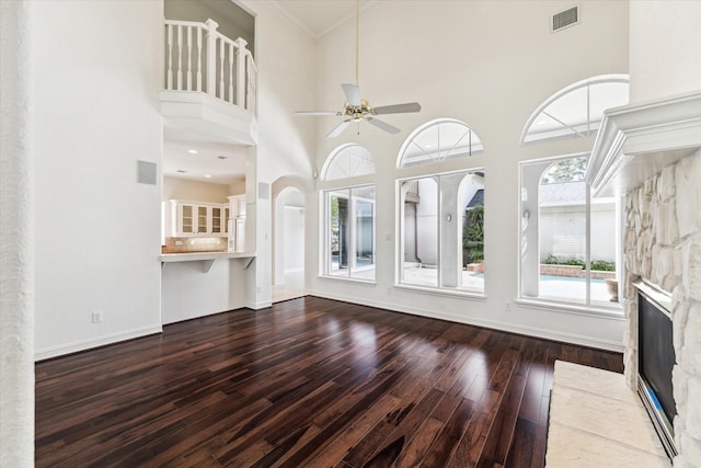 966 Bentwater Dr, Montgomery, TX 77356 - unfurnished living room featuring hardwood / wood-style flooring, ceiling fan, a stone fireplace, a towering ceiling, and crown molding