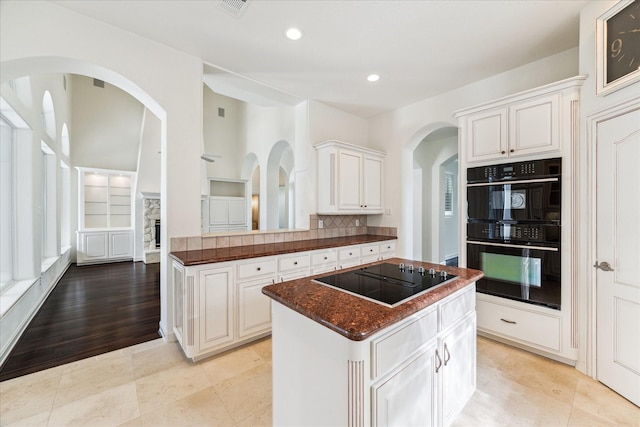 966 Bentwater Dr, Montgomery, TX 77356 - kitchen featuring black appliances, a kitchen island, arched walkways, recessed lighting, and white cabinetry