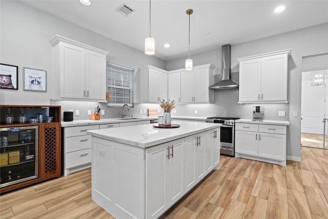 344 W 27th St, Houston, TX 77008 - kitchen with gas stove, wall chimney exhaust hood, wine cooler, white cabinetry, and recessed lighting